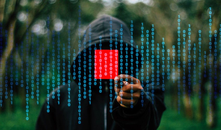 Hooded hacker against background of code