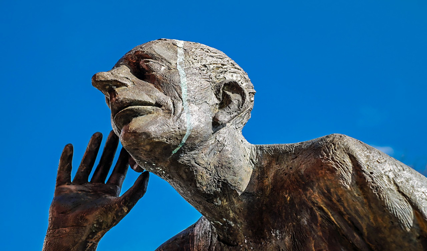 Sculpture of man listening with hand cupped to ear
