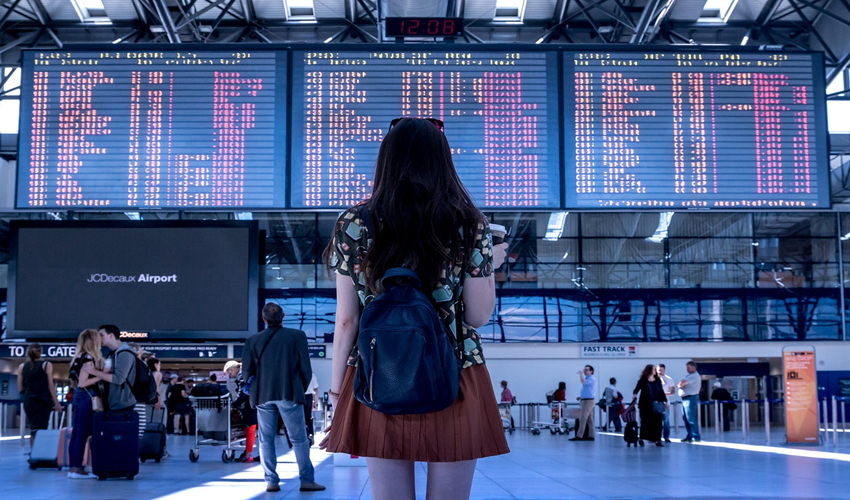 Woman standing in front of airport departure board