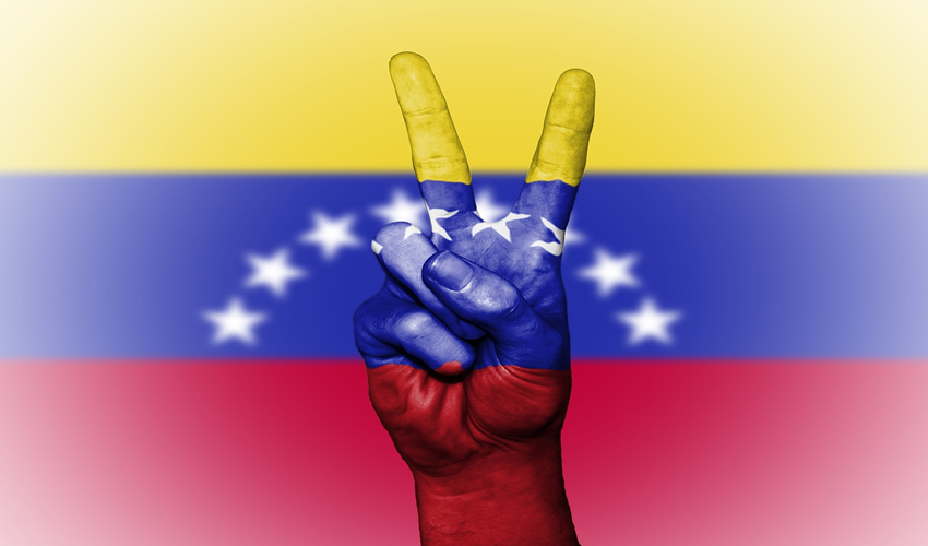 Peace hand symbol against backdrop of Venezuelan f;lag