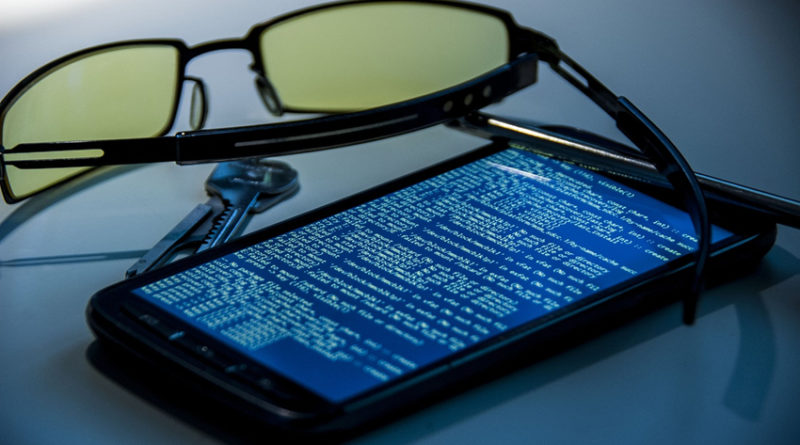 Glasses and keys next to a smartphone with code on screen