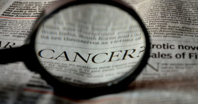 The word cancer viewed in a newspaper under a magnifying glass